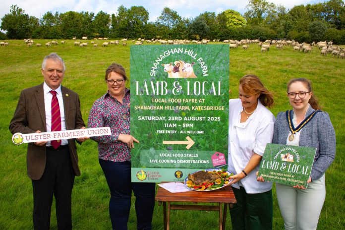 LAMB LOCAL-2 Four people standing in a field with food and a sign saying Lamb and Local.