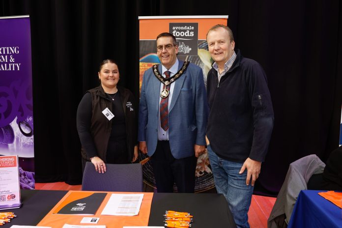 0058_ABC_LMP_ArmaghJob Three people standing in front of a sign at a careers fair