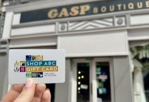 A hand holding a Shop ABC Gift Card outside Gasp Boutique