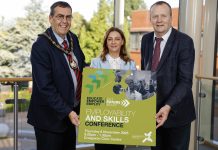 Three people holding a board that has details of the employability and skills conference taking place in Craigavon.
