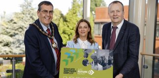Three people holding a board that has details of the employability and skills conference taking place in Craigavon.