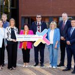 A group of people standing outside a building holding a sign that says Armagh City, Banbridge and Craigavon Labour Market Partnership.