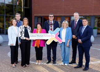 A group of people standing outside a building holding a sign that says Armagh City, Banbridge and Craigavon Labour Market Partnership.