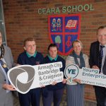 A group of people standing outside Ceara School holding ABC Council logo and Young Enterprise NI logo.