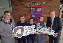 A group of people standing outside Ceara School holding ABC Council logo and Young Enterprise NI logo.