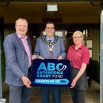 Three people standing in a doorway holding a sign that says ABC Enterprise Grant Fund