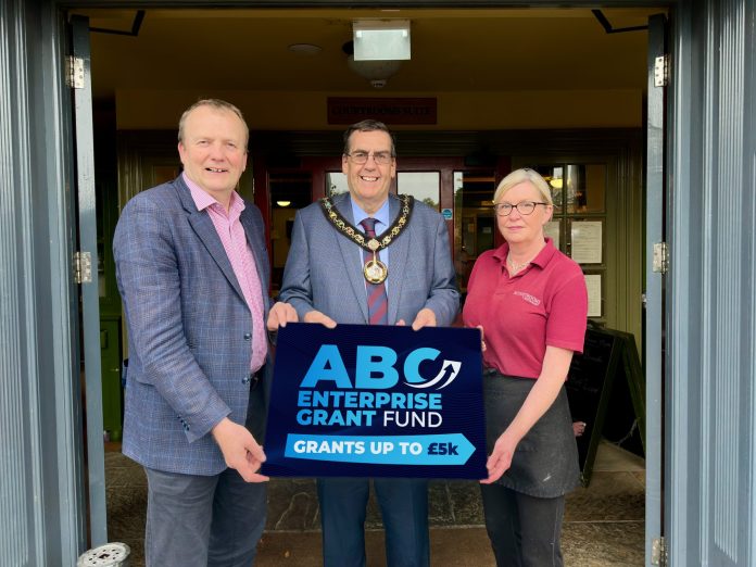 Three people standing in a doorway holding a sign that says ABC Enterprise Grant Fund