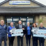 Active habits creating energy and fun at St Anthony’s PS! Six staff from St Anthony's Primary School standing outside the school holding signs to promote the council's Get Moving programme.
