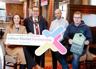 Four people standing in a bar restaurant holding a sign that says Labour Market Partnership