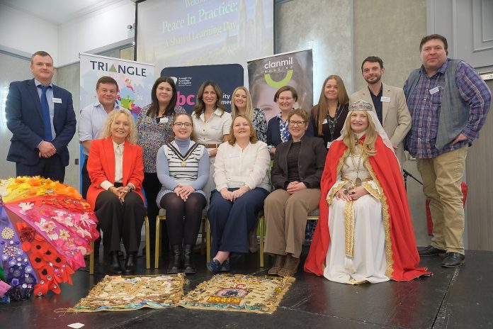 A group of people on stage at the Peace in Practice shared learning day.
