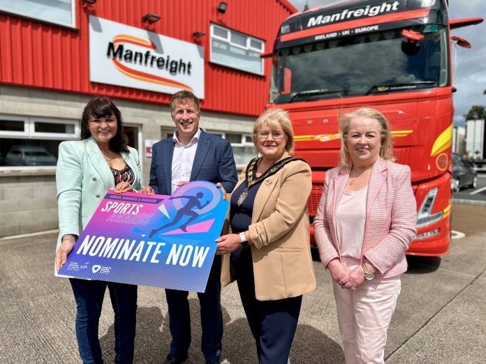 4 people standing in front of a Manfreight Ltd lorry holding a banner promoting the junior sports awards.