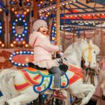 Young girl sitting on a merry go round horse