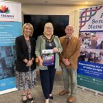 Three people standing in front of positive ageing month banners