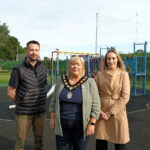 3 people standing in front of play equipment in a playpark.