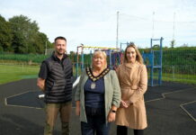 3 people standing in front of play equipment in a playpark.