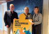 Three people holding a sign that says ABC Enterprise Week