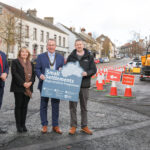 Final phase of £2m Environmental Improvement Scheme commences in Markethill Four people standing on a street with construction works to their left, holding a sign saying Small Settlements.
