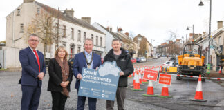 Final phase of £2m Environmental Improvement Scheme commences in Markethill Four people standing on a street with construction works to their left, holding a sign saying Small Settlements.